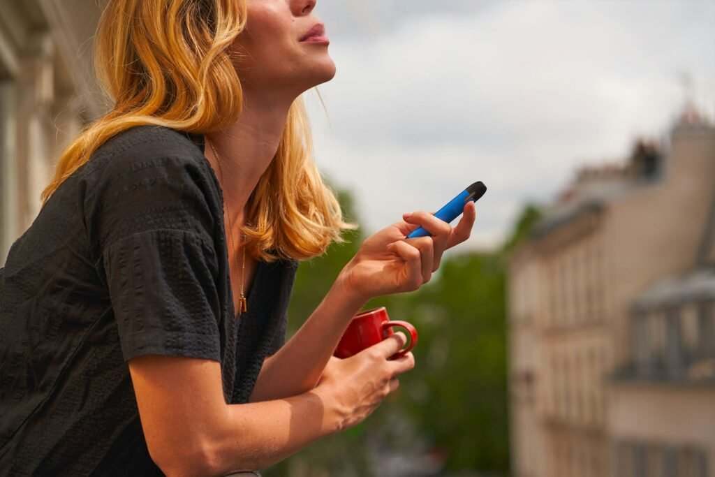Photo by Romain B a woman holding a cup and a cell phone